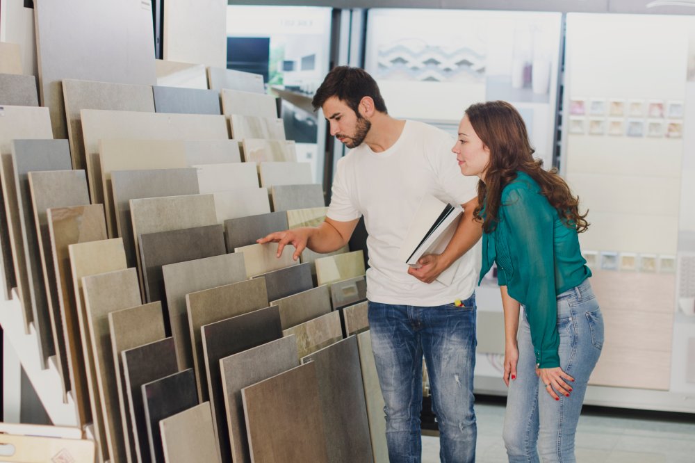 Couple looking ceramic and tiles for their new home floor. They are choosing in furnitures store