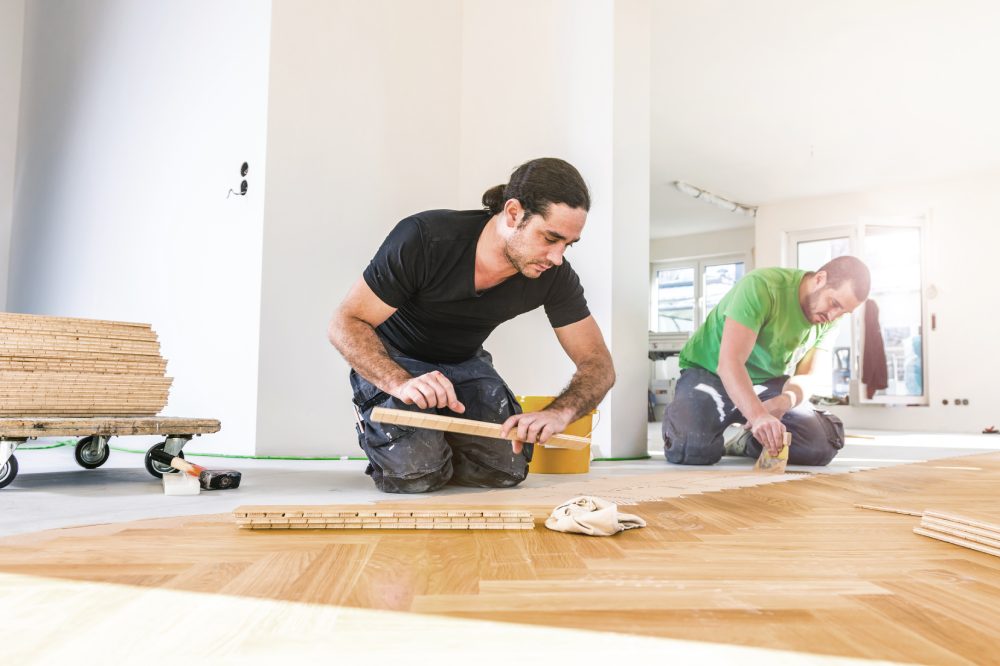 Carpenter on work putting wood parquet pieces. Home construction