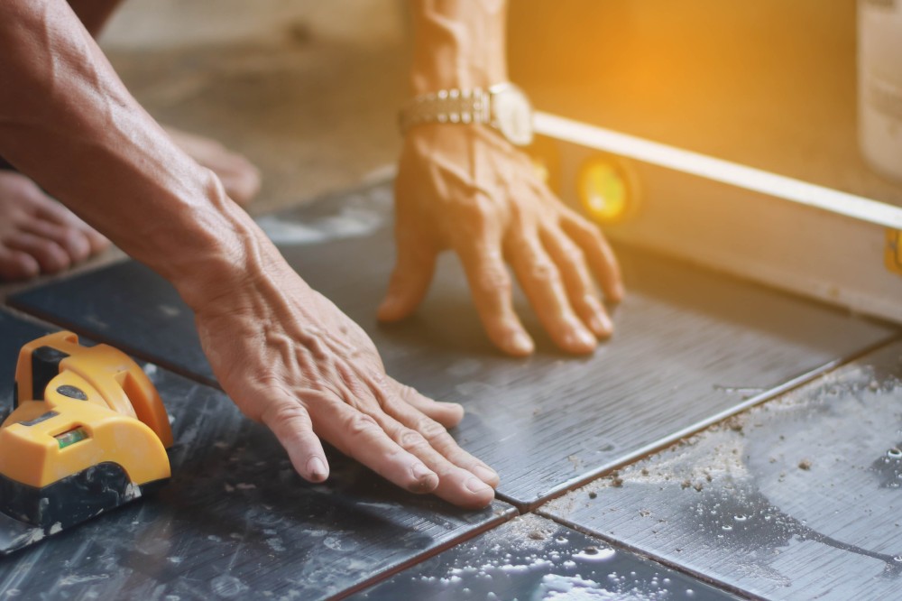 ceramic tiles. the worker's hand tile in position over adhesive with lash tile leveling system.selective focus.vintage tone