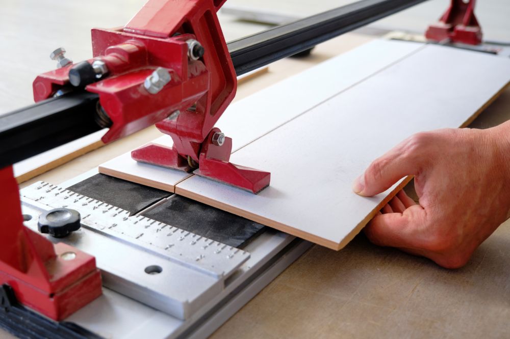 close-up of a work tool using manual cutting equipment for laying, processing ceramic tiles. Red tile cutter